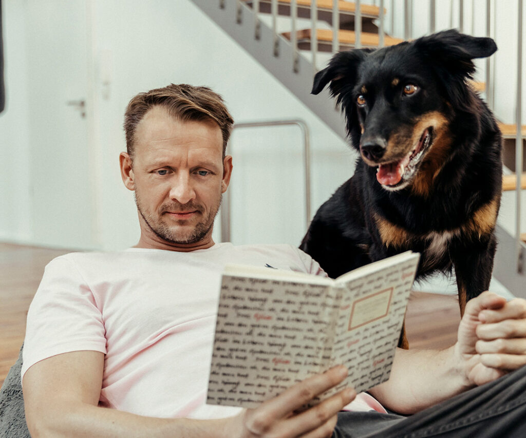 Franz Spitzer,hält Buch in der Hand während er Hund hinschaut